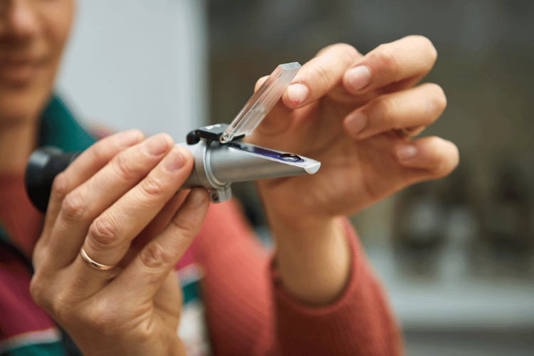 A woman using a refractometer for measurement